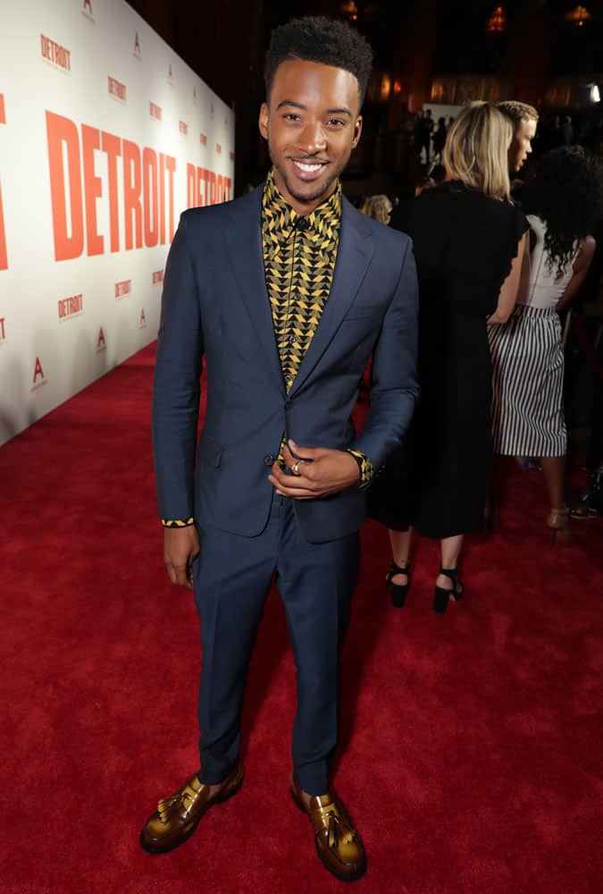Algee Smith wearing a navy suit and printed shirt at the Detroit premiere