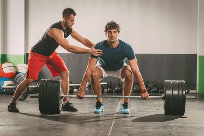 A Personal Trainer Working With Someone On A Deadlift