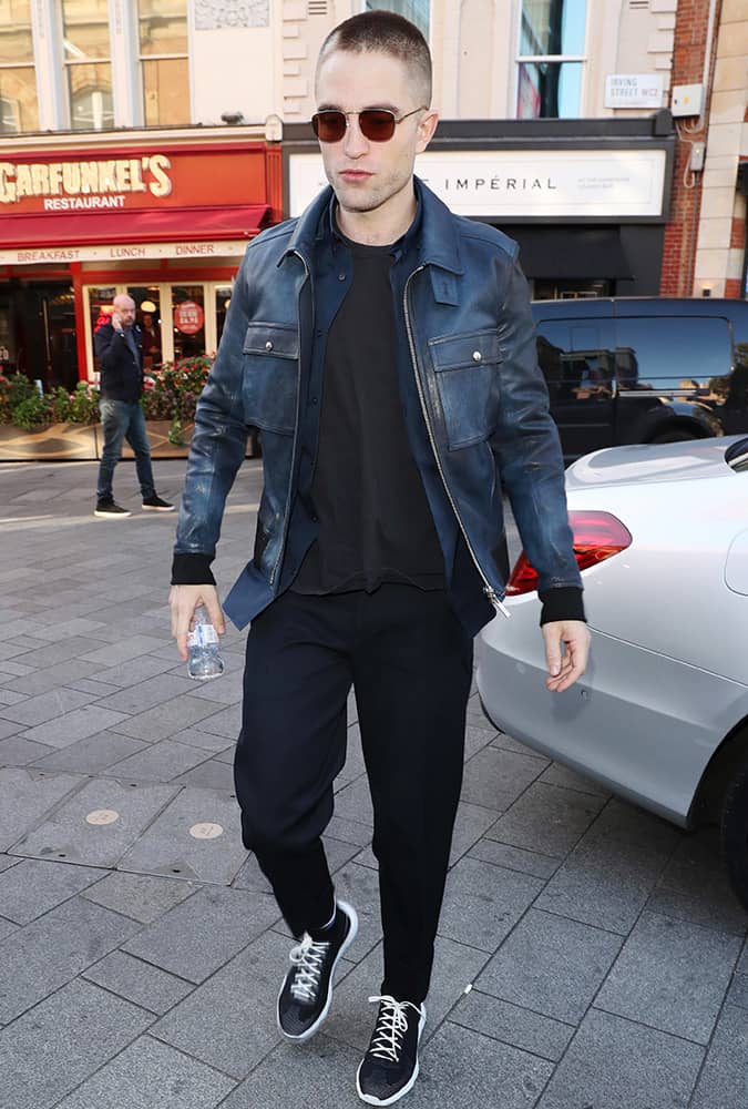 Robert Pattinson with a shaved head and wearing a leather jacket