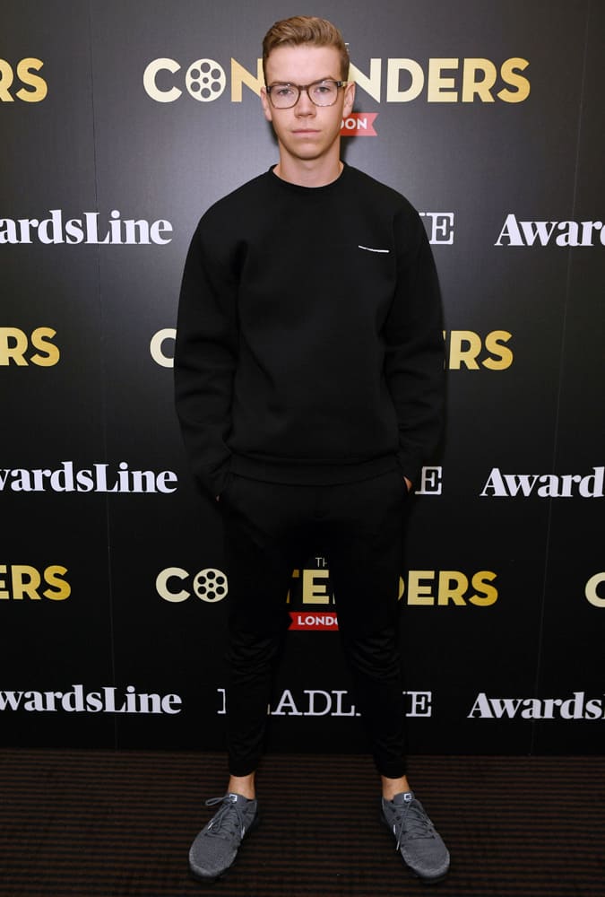 Will Poulter wearing all black sportswear and glasses