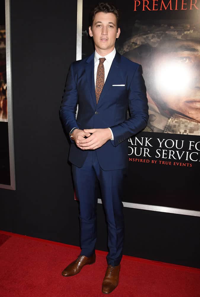 Miles Teller wearing a navy suit and orange floral tie