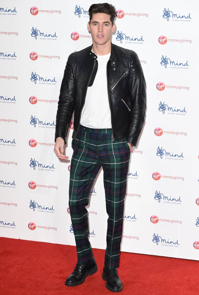 Isaac Carew wearing check trousers and a leather biker jacket