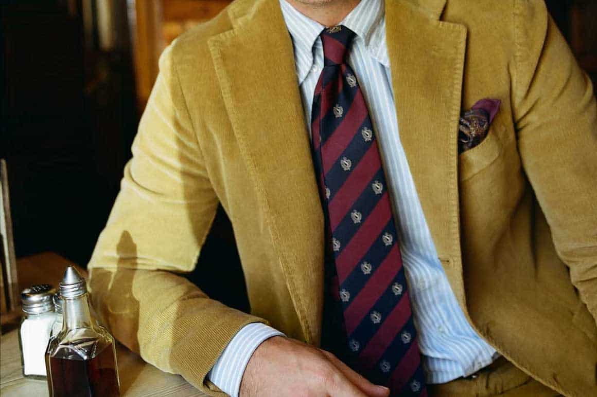 man wearing yellow suit with red striped tie
