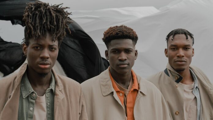 Men with Braids wearing trench coats Standing with grey background
