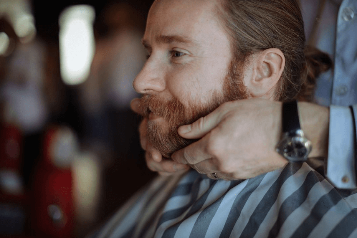 Barber using beard balm on clients beard