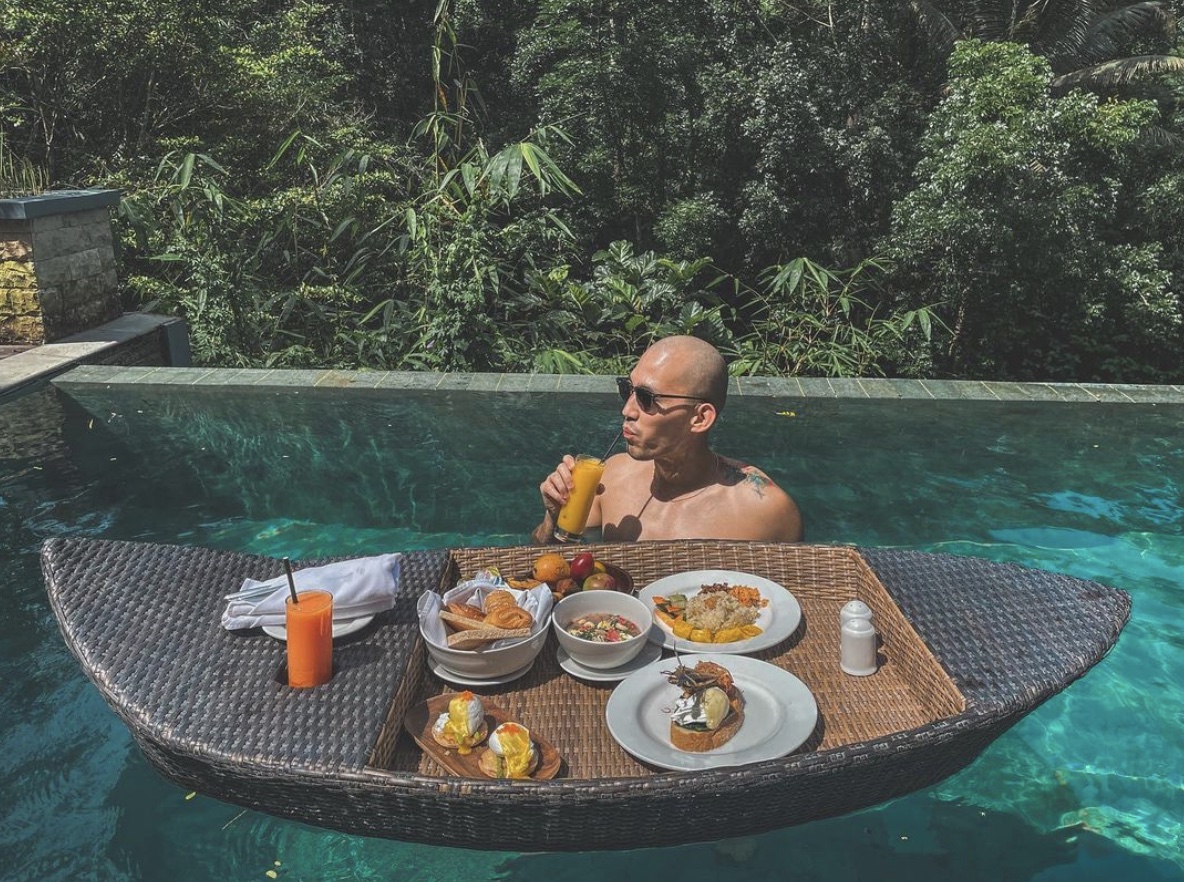 Bald man in a pool with breakfast laid out on a floating table