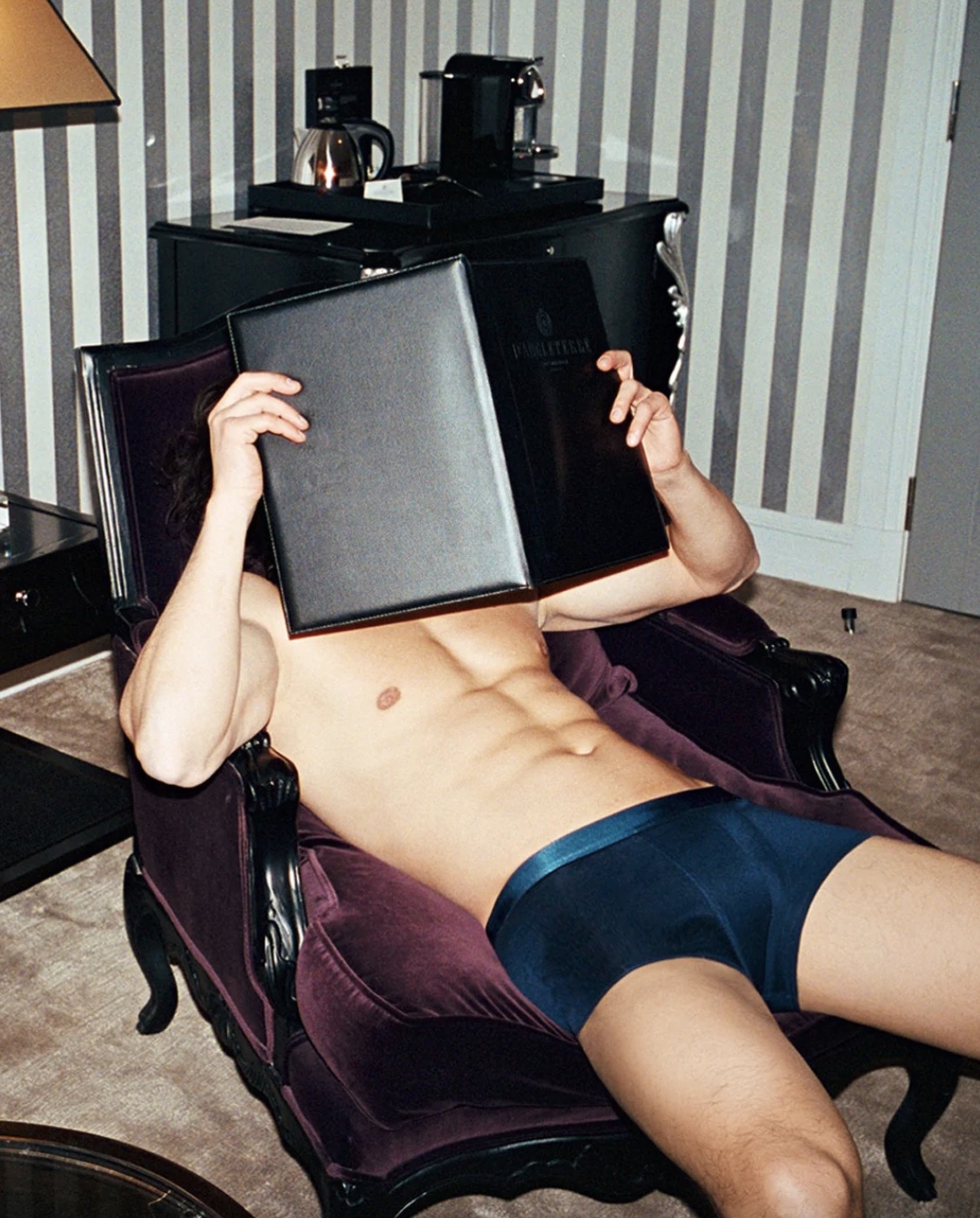 CDLP underwear model leaning back on a chair face covered with a book