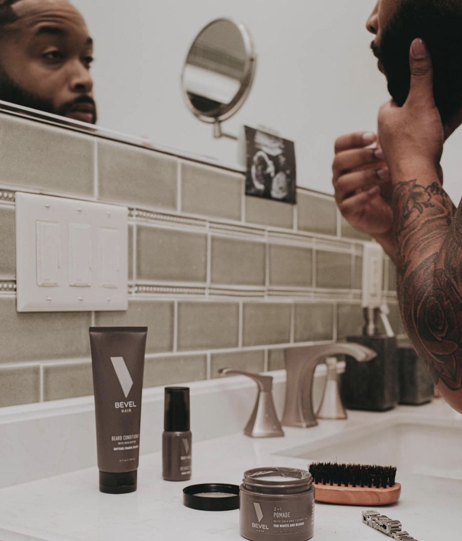 man looking in the mirror with shaving products on the counter