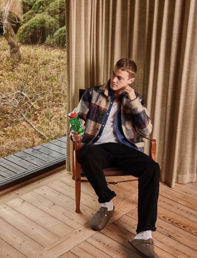 man sitting in a chair wearing Foret clothing and holding a water bottle