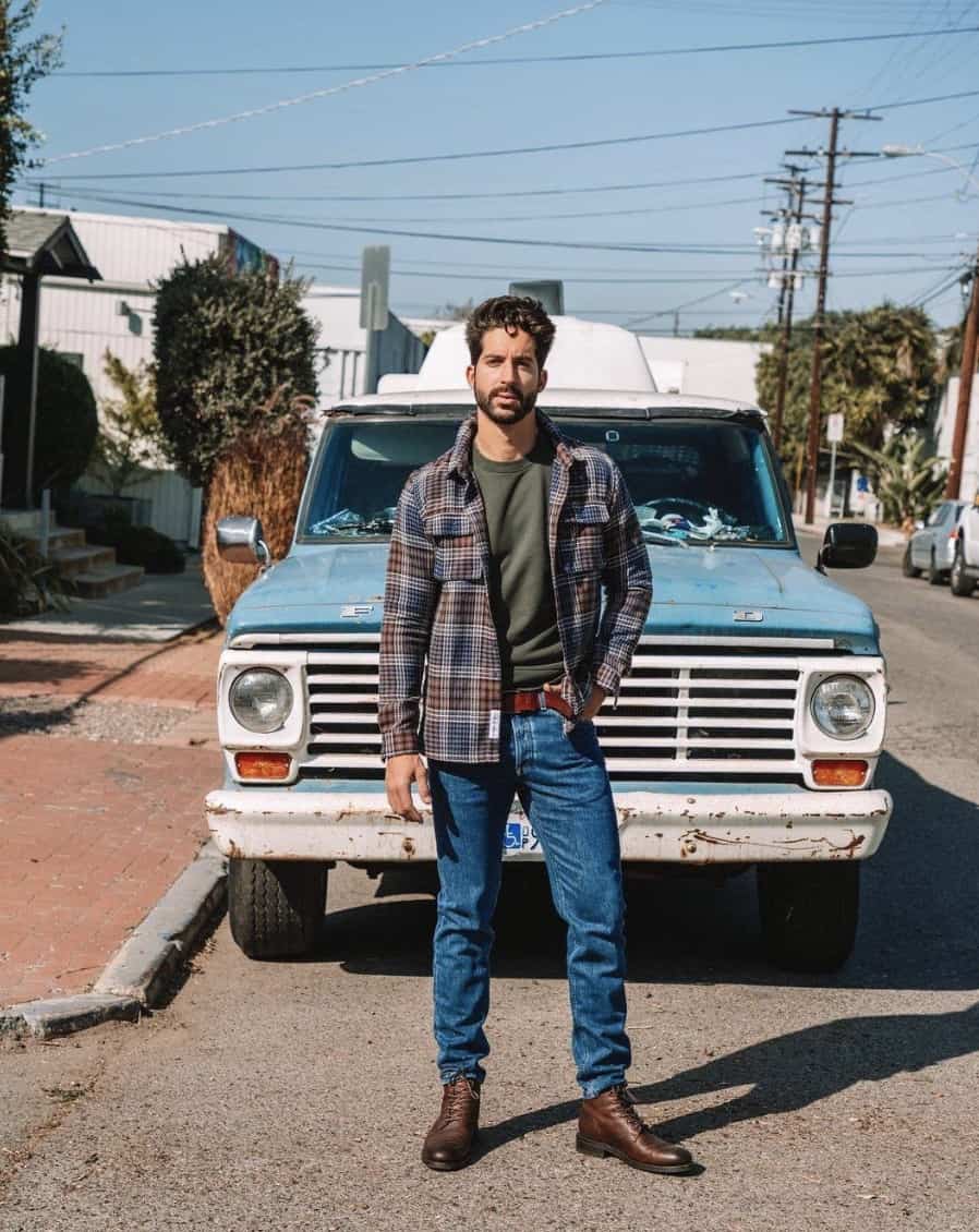 man standing in front of a blue pick-up truck, looking at the camera