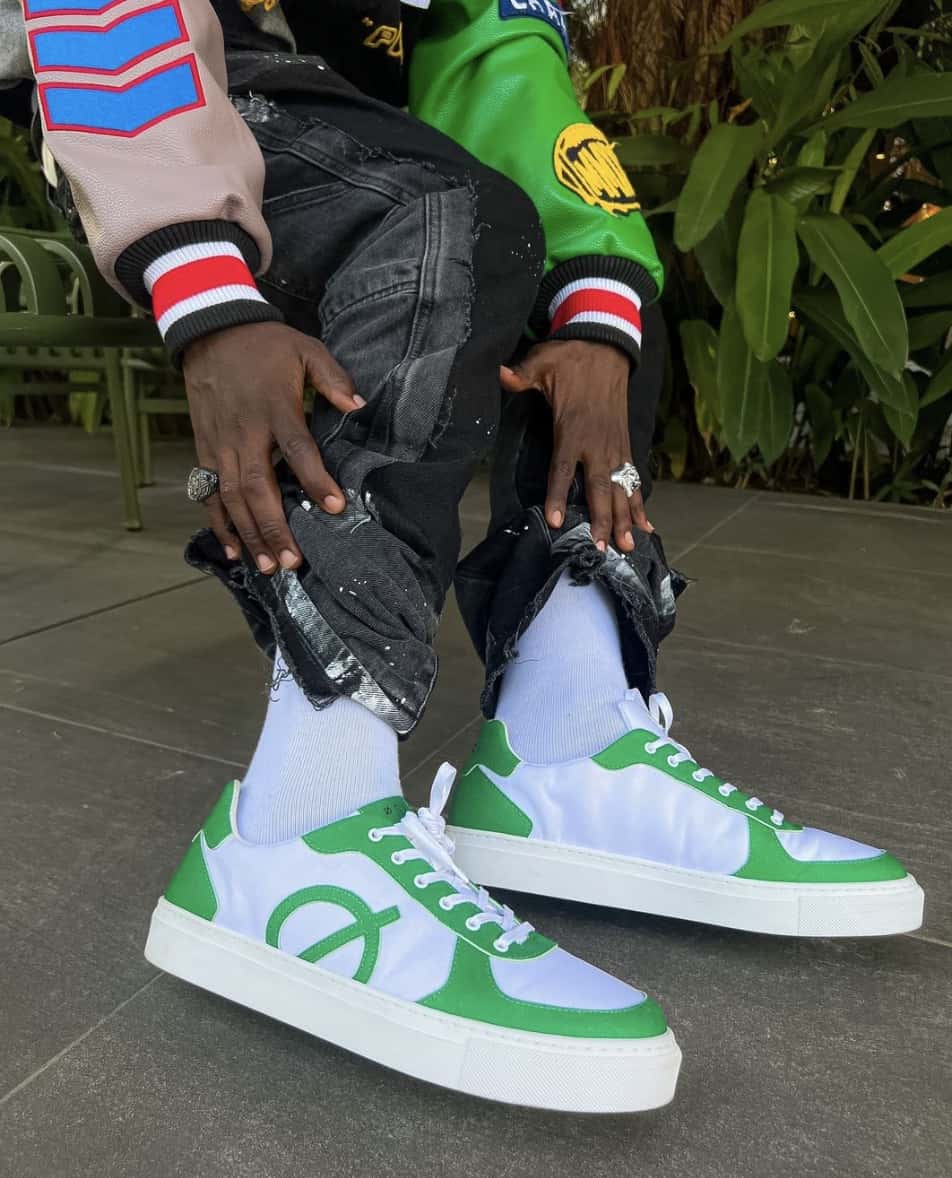 man showing off white socks and green and white sneakers