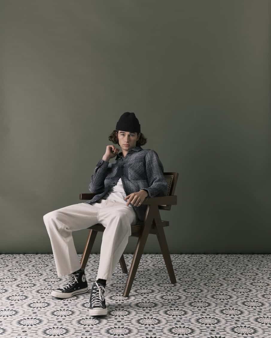 Man sitting on a chair in front of a green wall an tiled floor