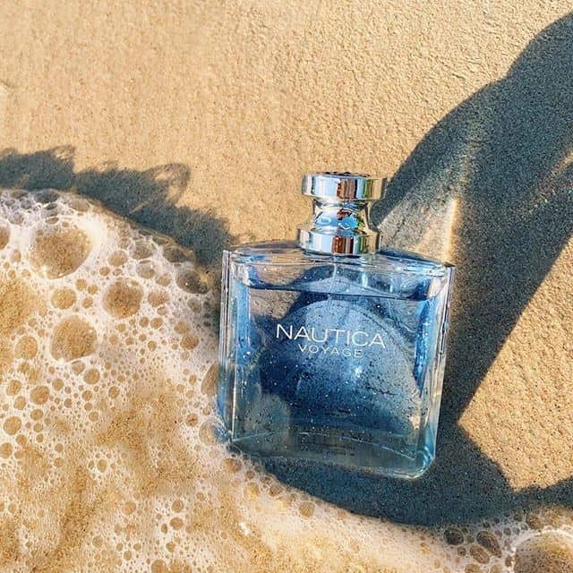 a bottle of nautica voyage laying on the beach