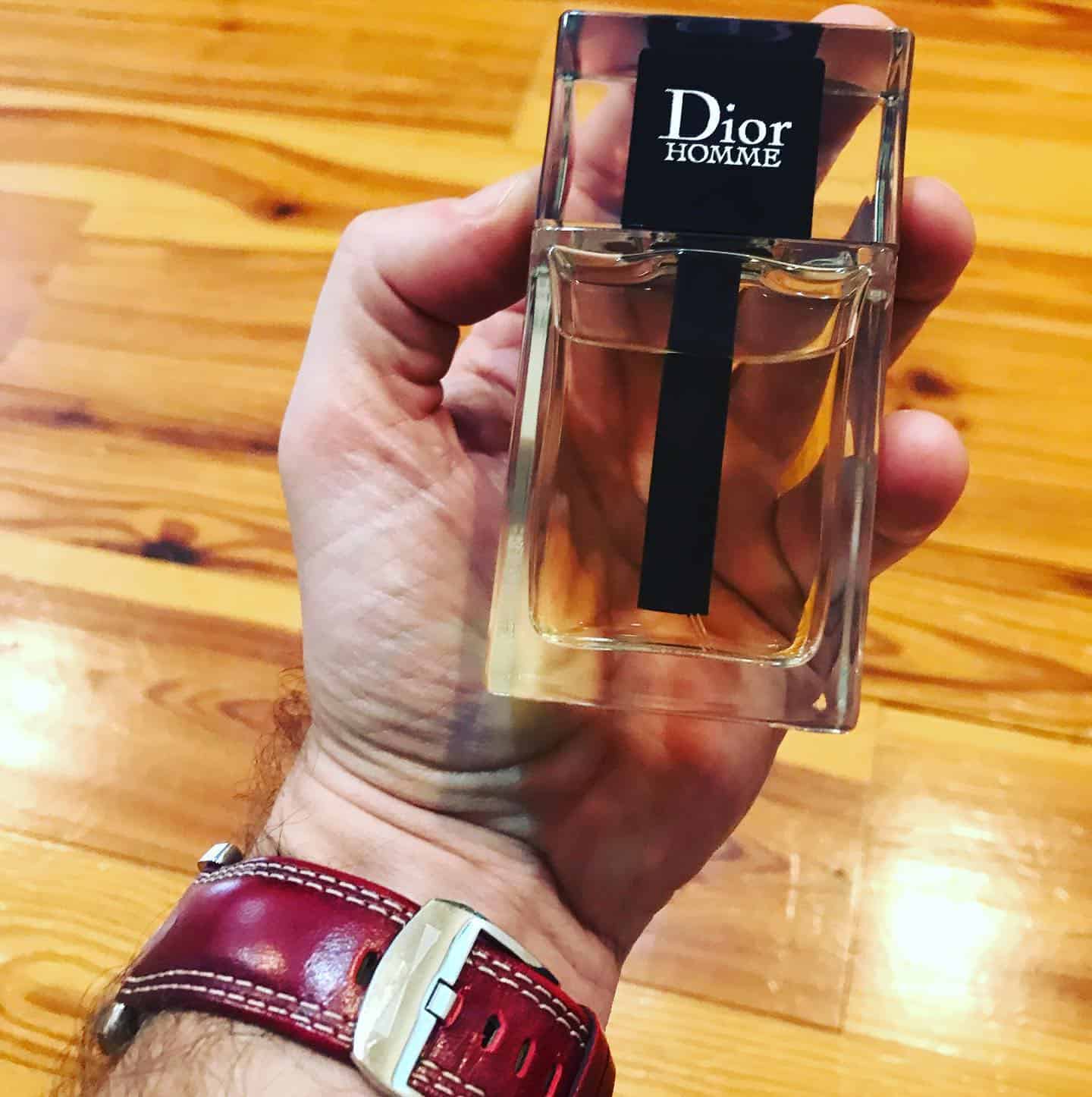 holding a bottle of Dior Homme