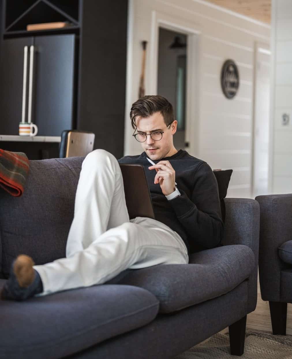 man sitting on a couch wearing Mott & Bow Jeans looking at an IPad