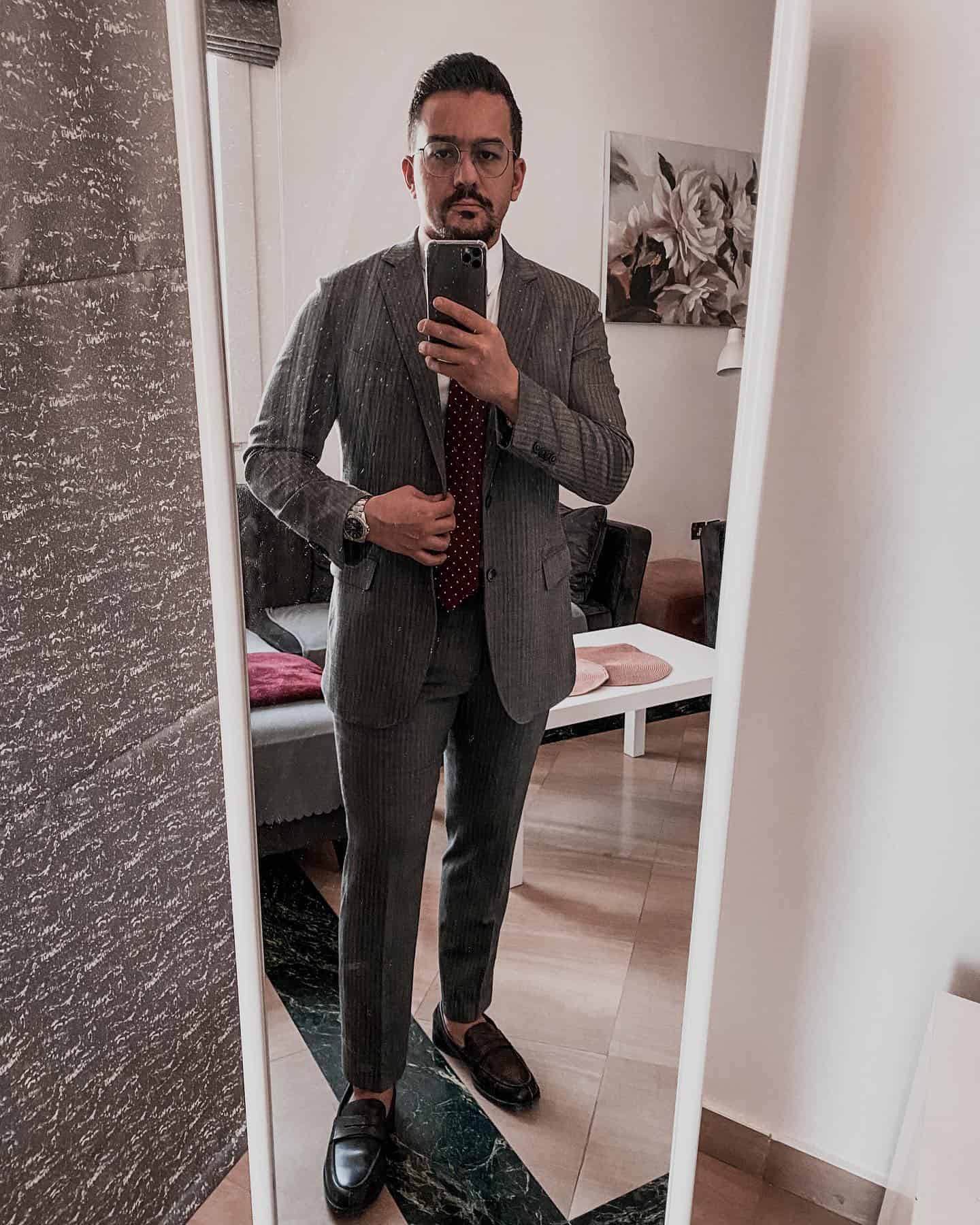 man in a gray suit taking a mirror selfie
