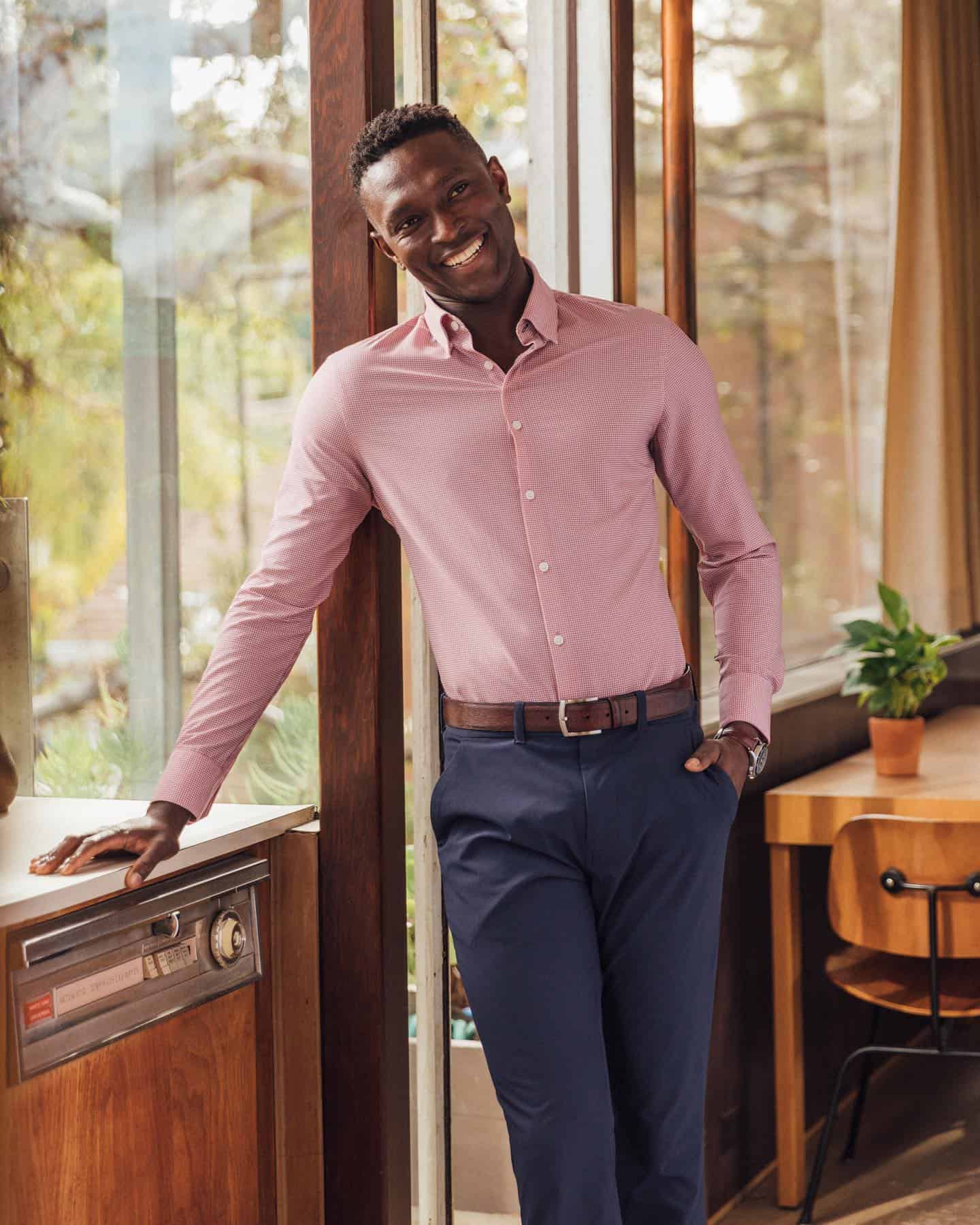 man in a slim fit pink shirt leaning on a counter top