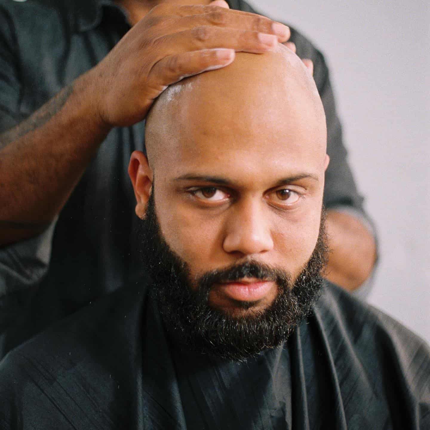 a barber applying cream to a shaved head
