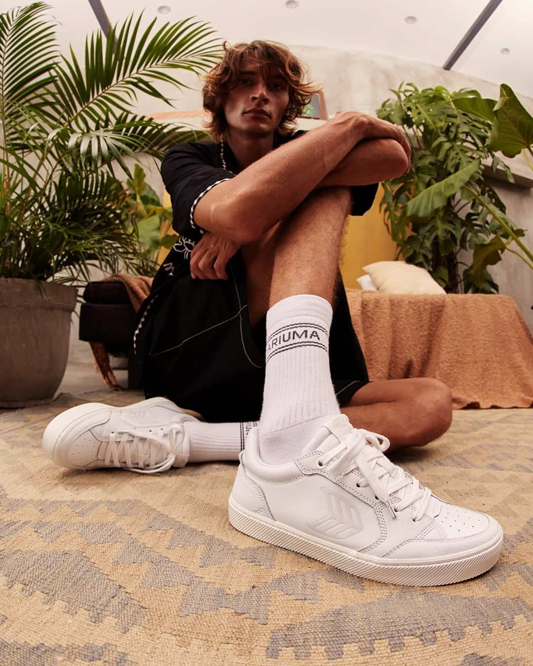 man sitting on the floor wearing a pair of white sneakers