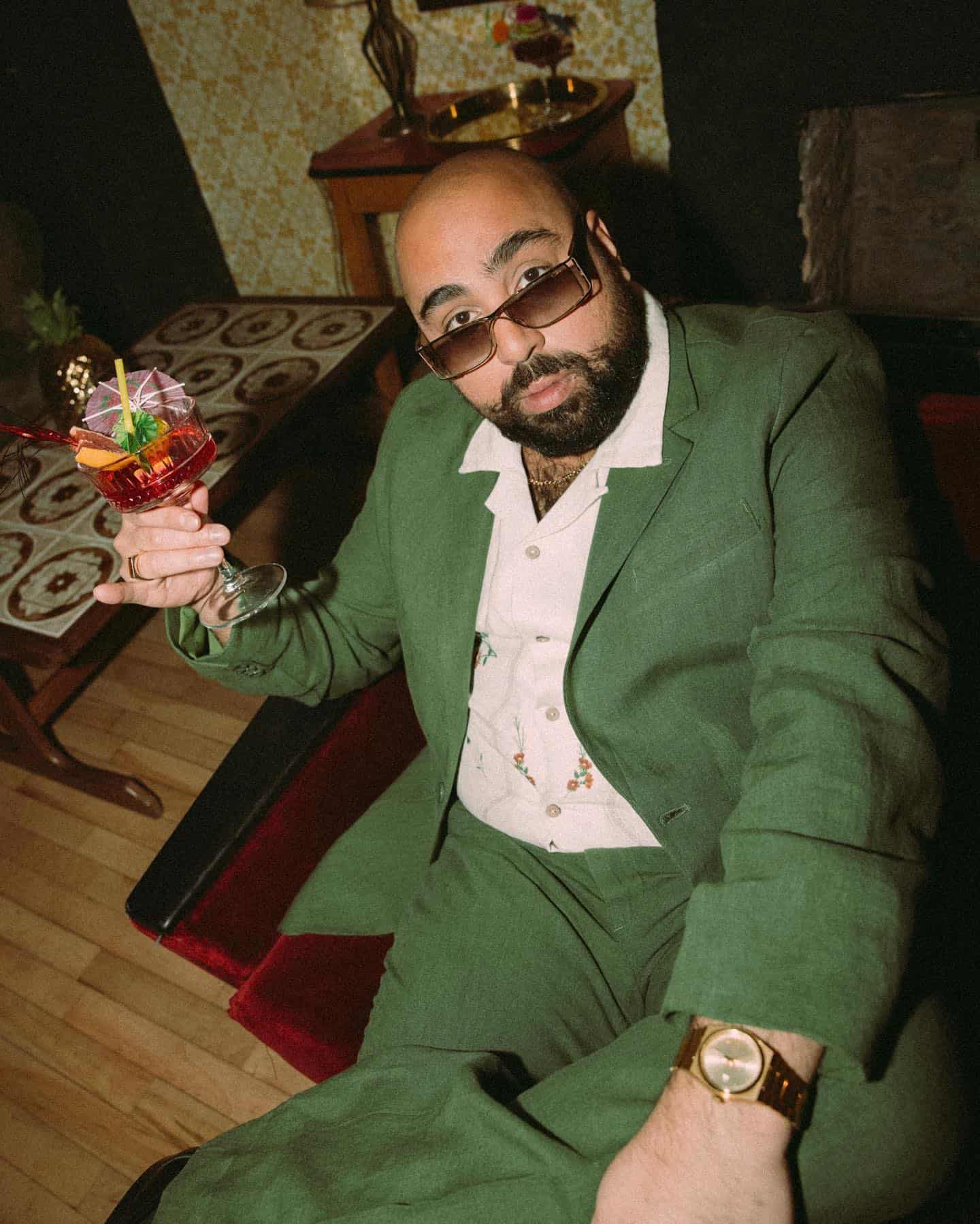 man in a green suit holding a drink
