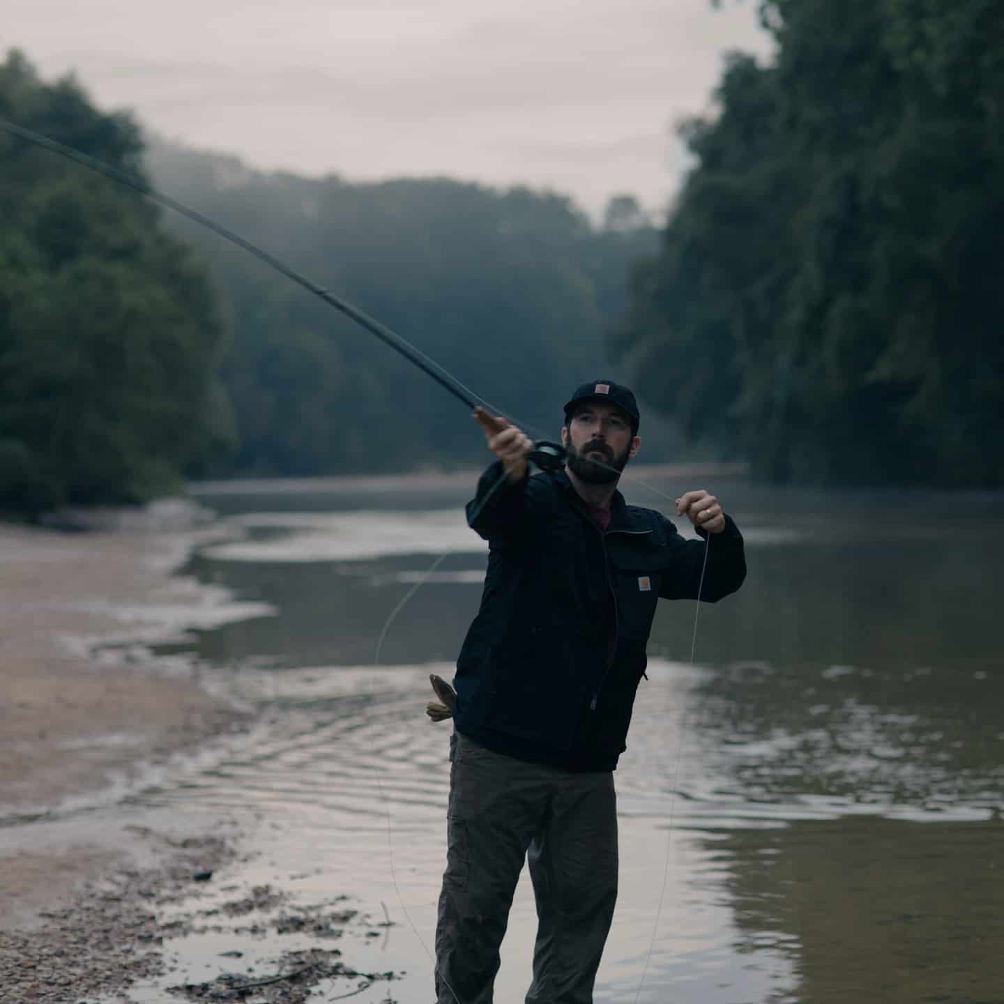 man casting a fishing line into the river