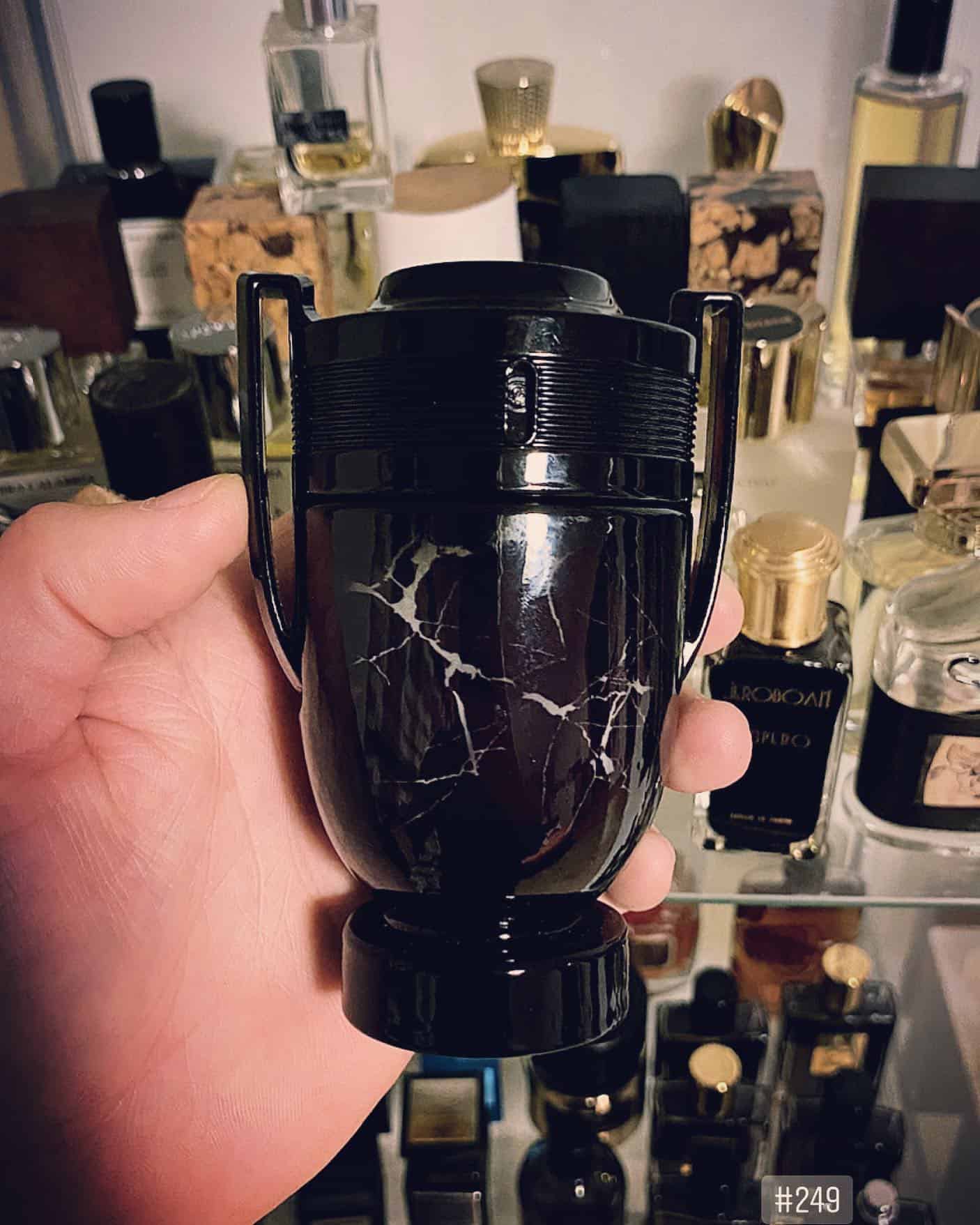 holding a bottle of invictus onyx by paco rabanne