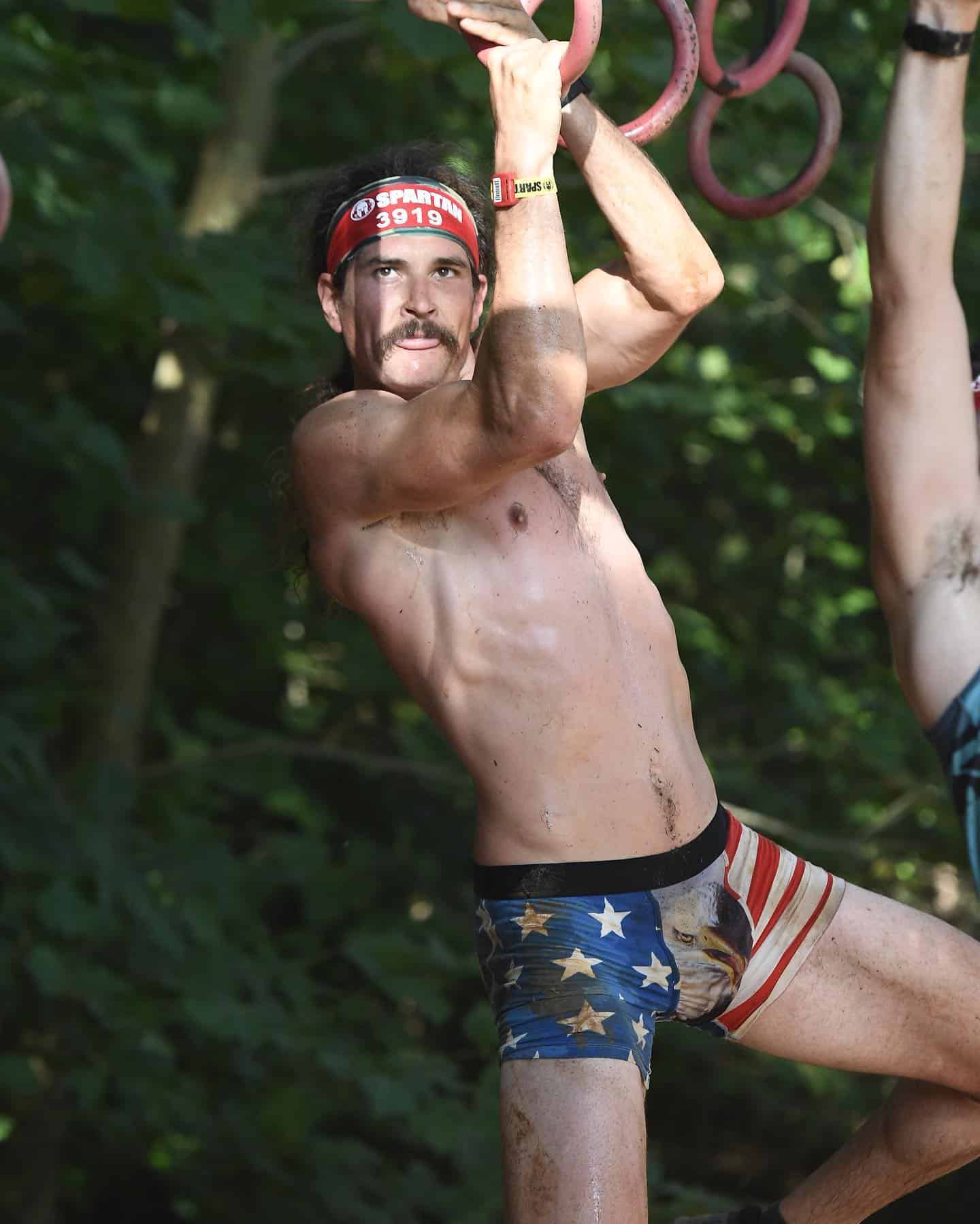 man hanging from a monkey ring course