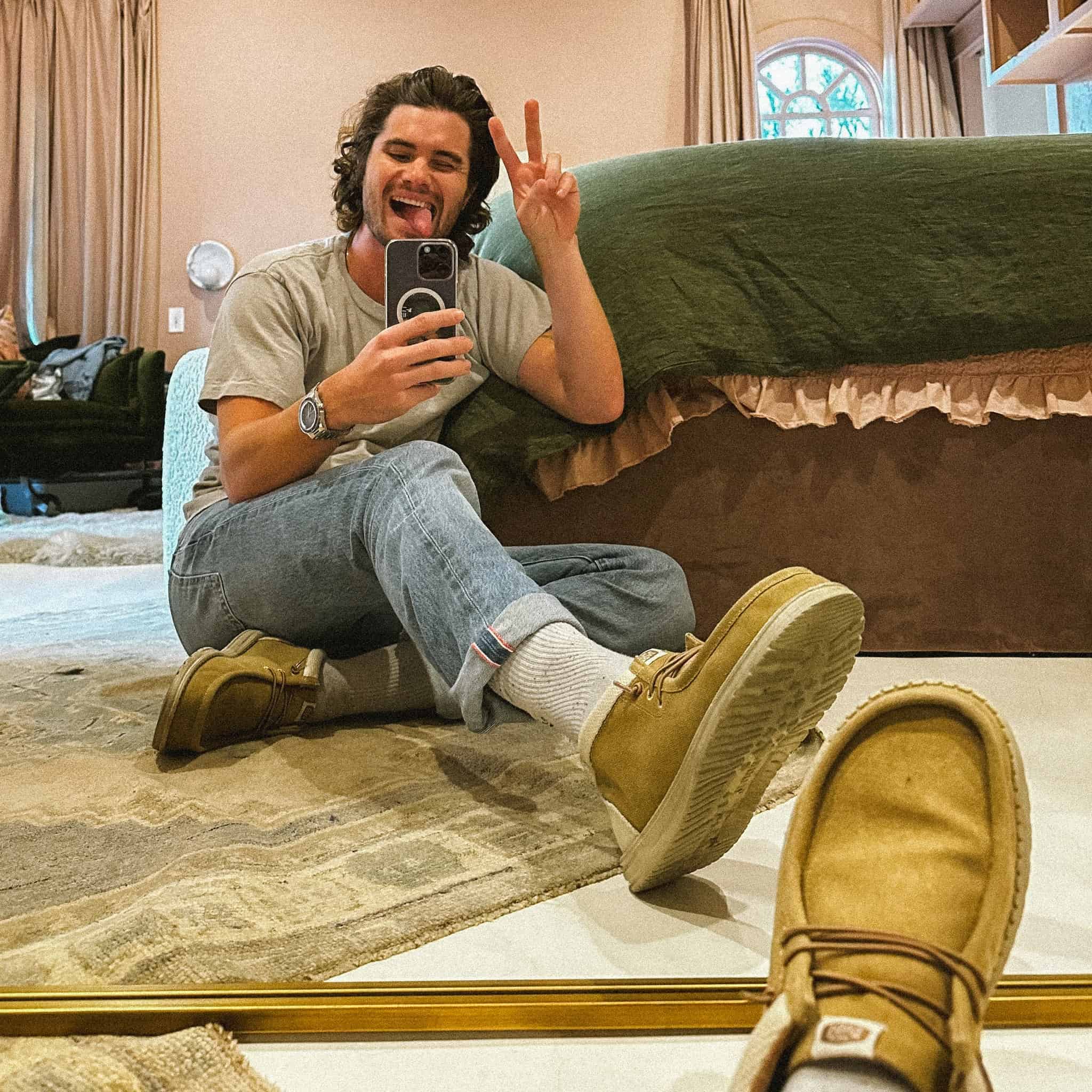 man taking a mirror selfie and throwing a peace sign