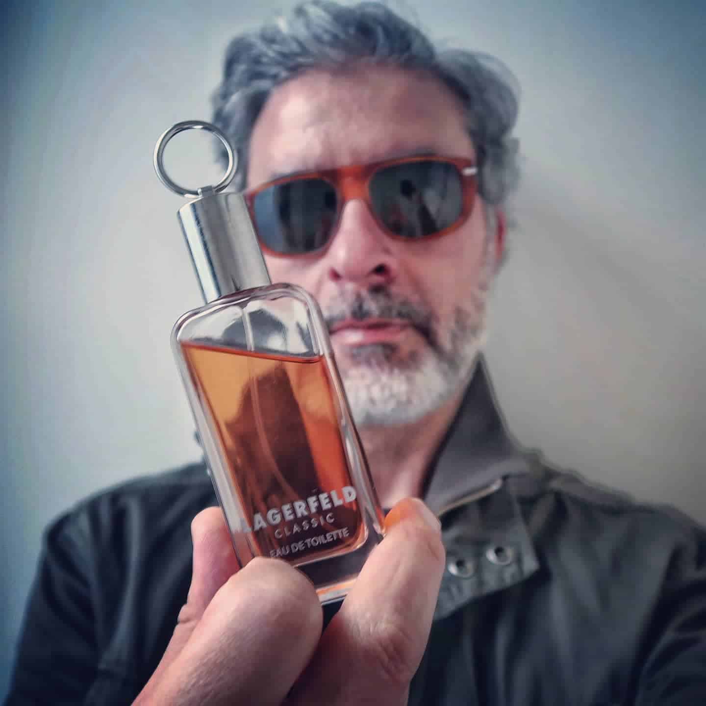 man holding a small bottle of lagerfeld classic cologne