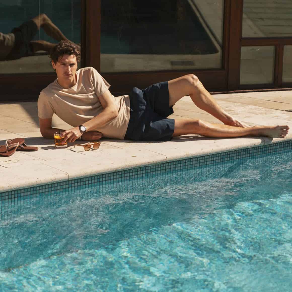 man having a cocktail drink beside a pool