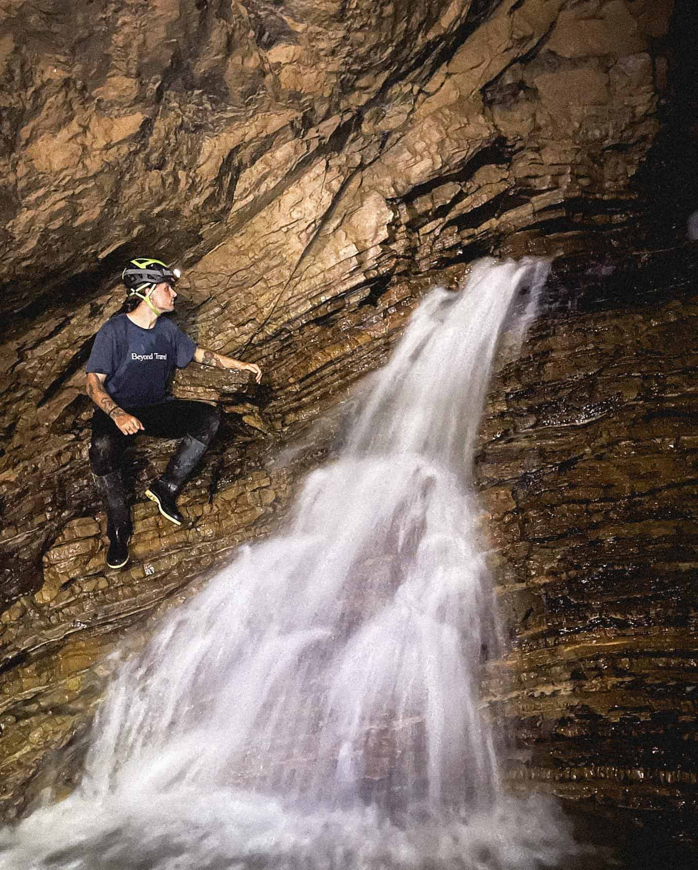 man checking a waterfall in a cave
