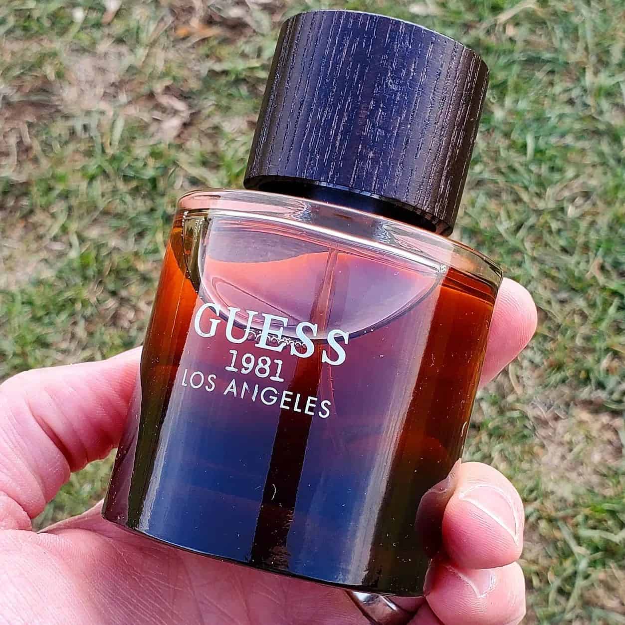 holding a bottle of 1981 los angeles cologne by guess