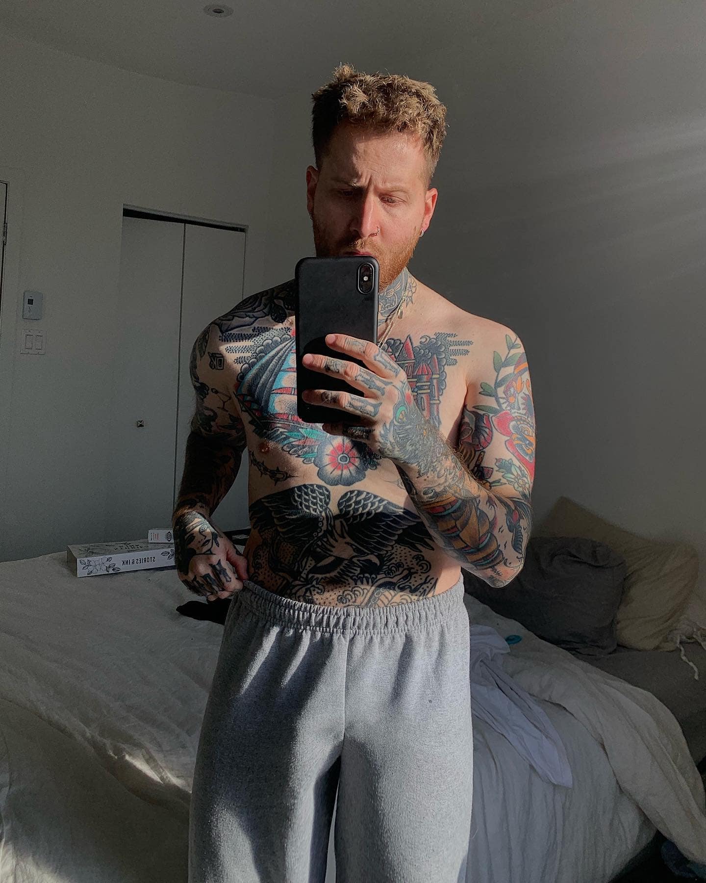 shirtless man with tattoo taking a mirror selfie