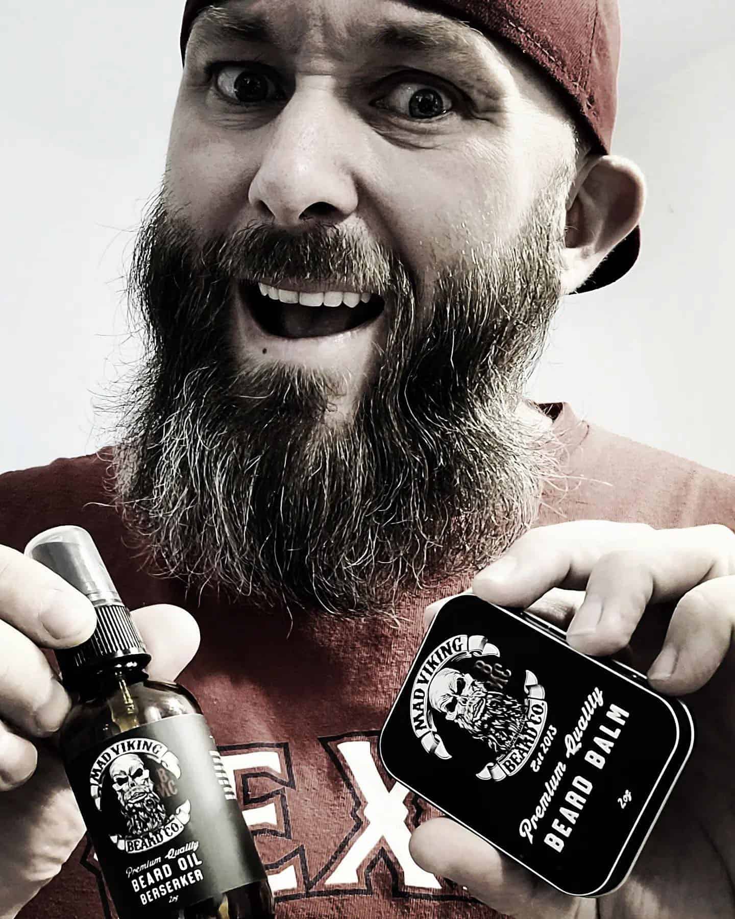 man holding a beard oil and a beard balm by mad viking