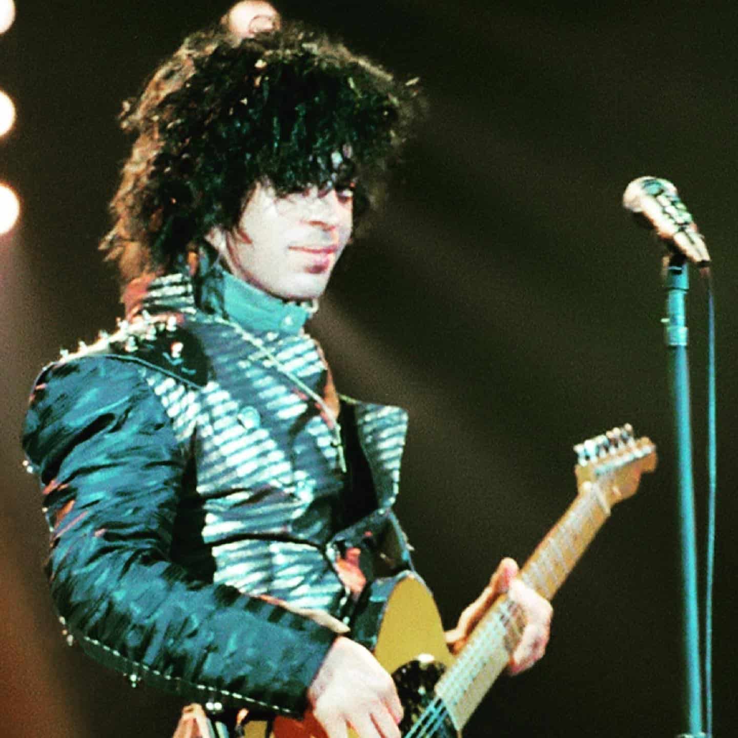 prince playing the guitar in a concert
