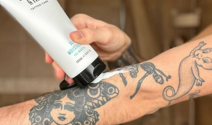 man applying a tattoo care lotion on arm