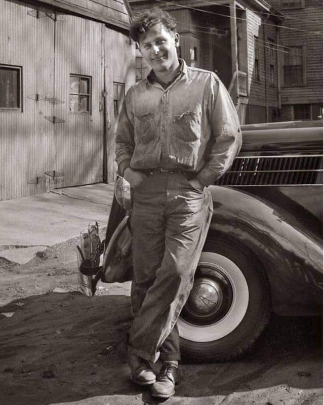 man in 1950s standing with legs crossed and hands inside the pants pocket