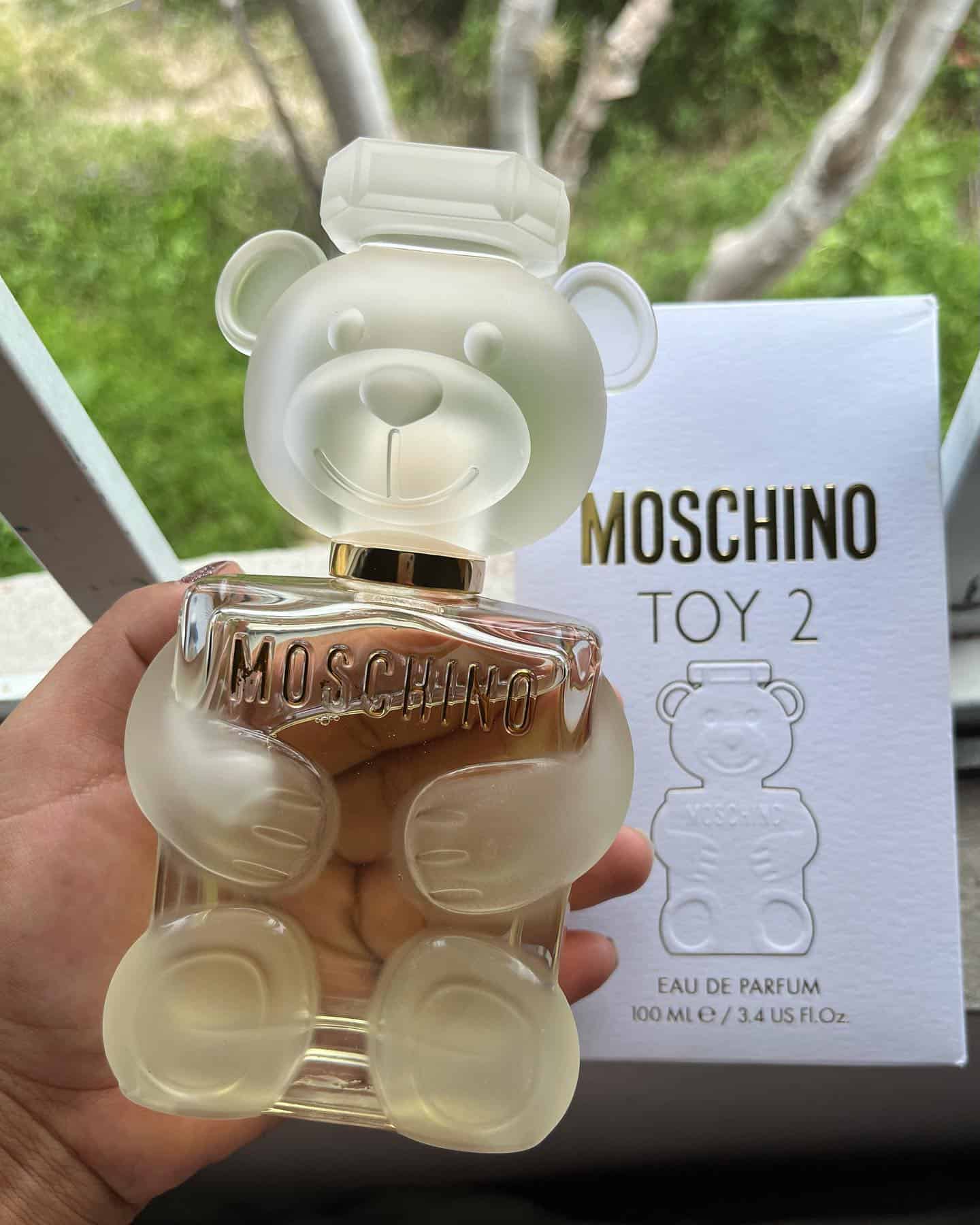 holding a bottle of moschino toy 2 cologne