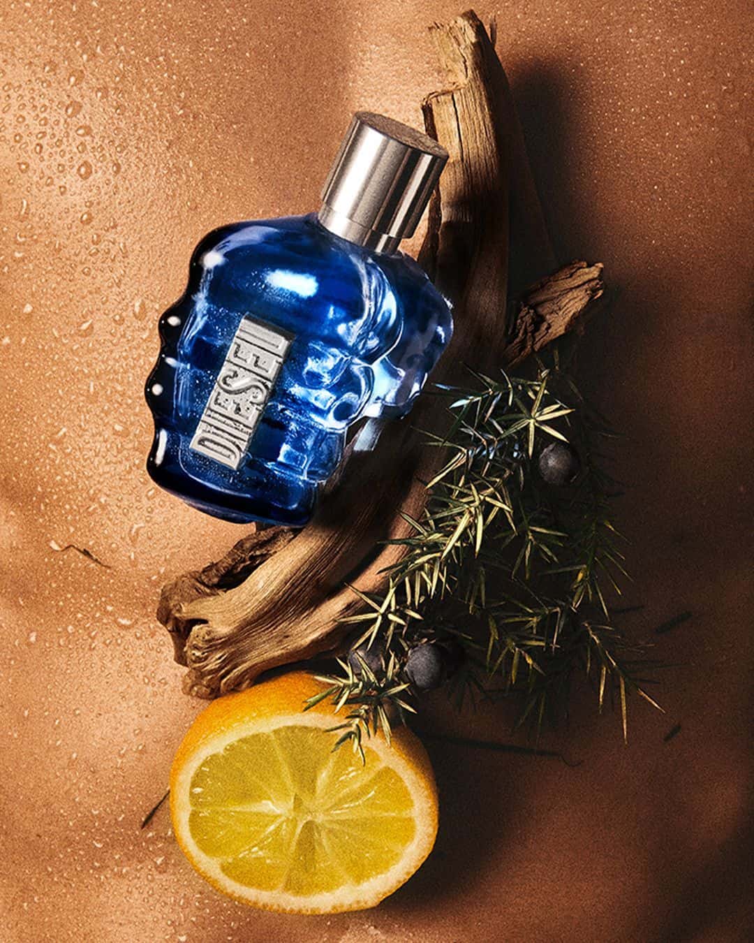 a bottle of only the brave cologne by diesel with some of the raw ingredients