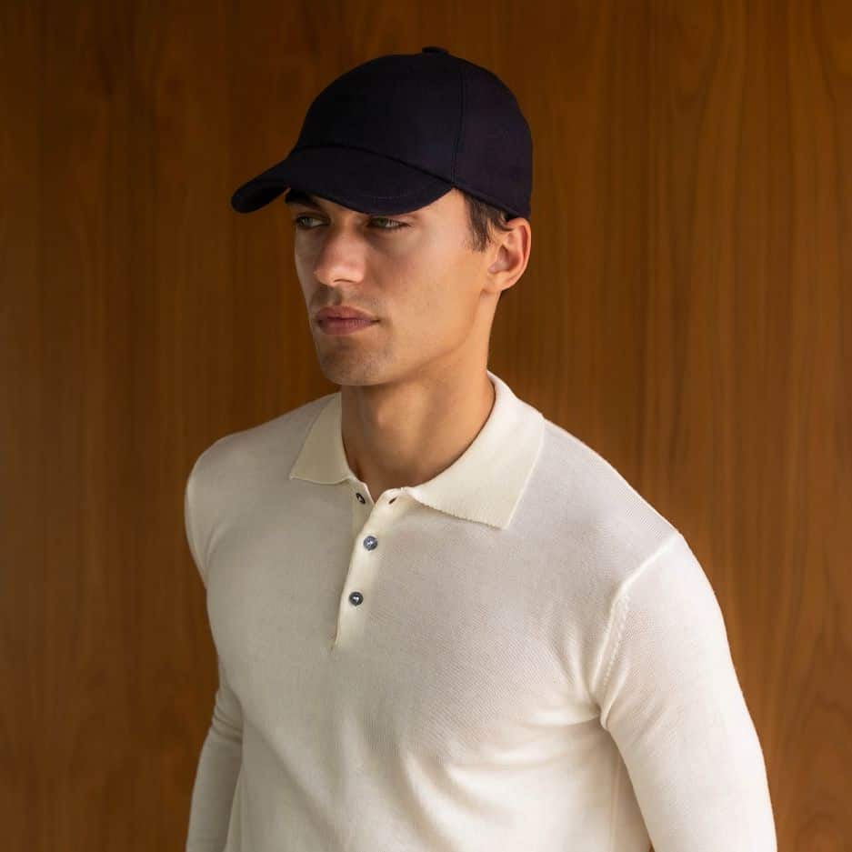 man wearing a black hat and an off-white long sleeved polo shirt