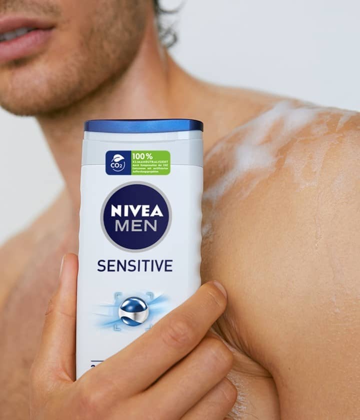 man holding a bottle of nivea men sensitive body wash