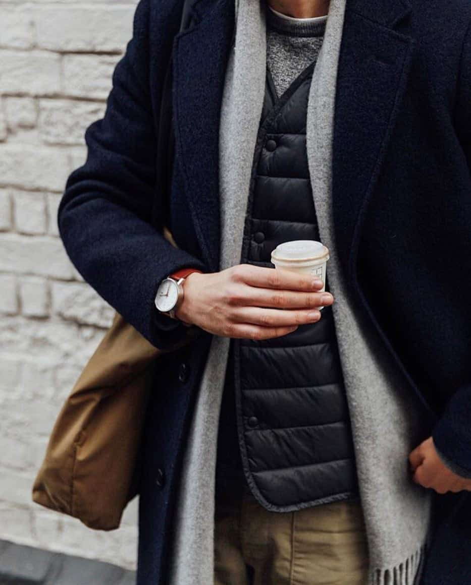 homem vestindo um casaco de lã enquanto segura uma xícara de café