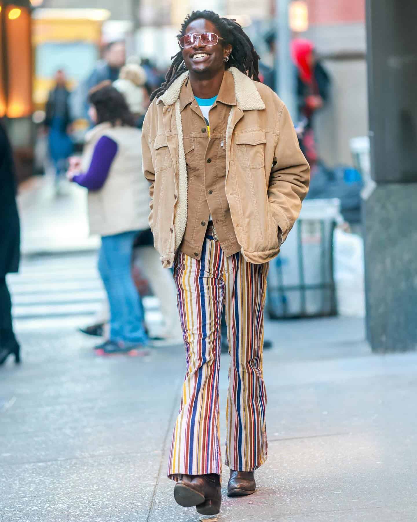 man with dreadlocks wearing a colorful stripped jeans