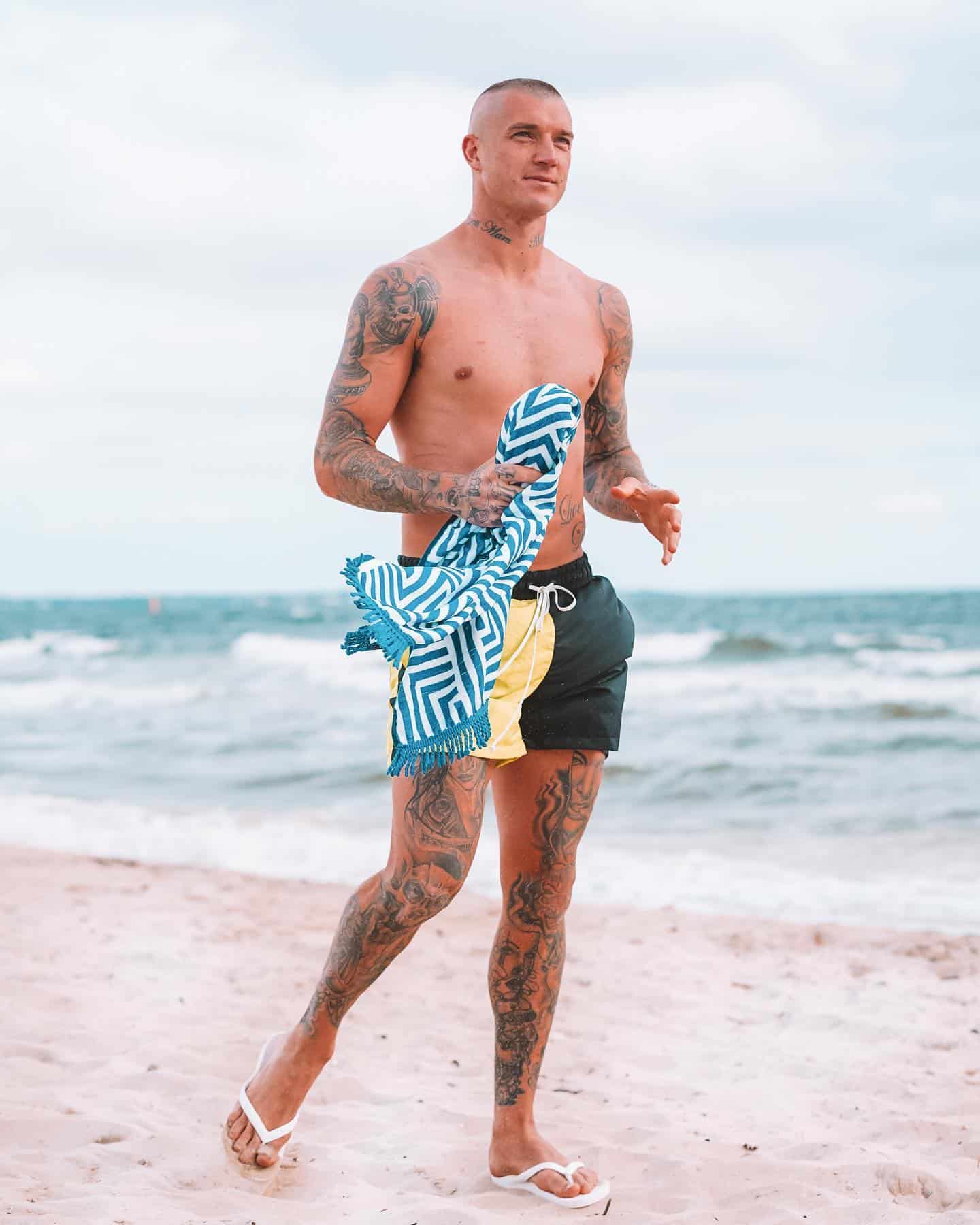 man walking at the beach wearing shorts and flip flops