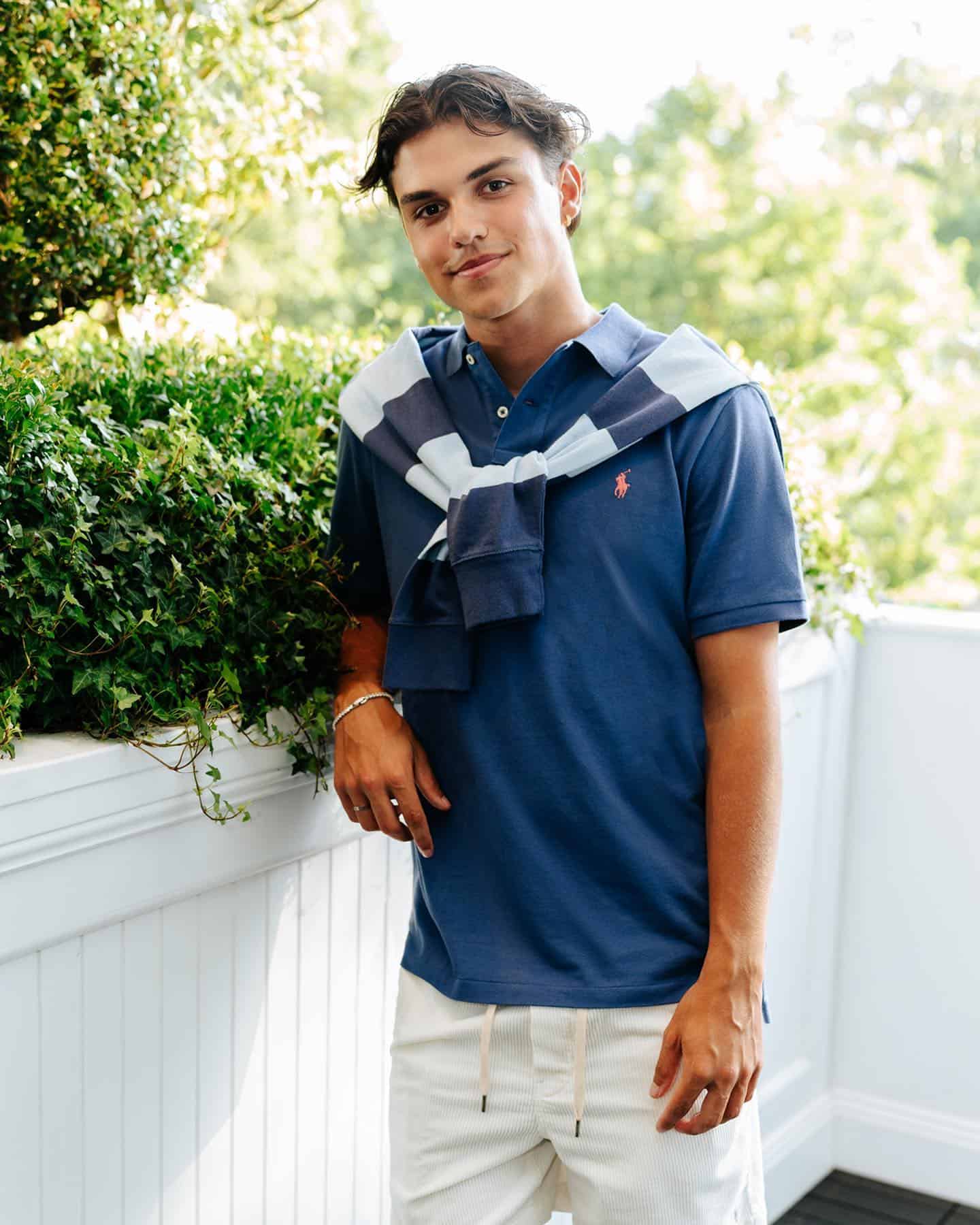 man wearing a navy blue polo shirt with sweater tied around the shoulders