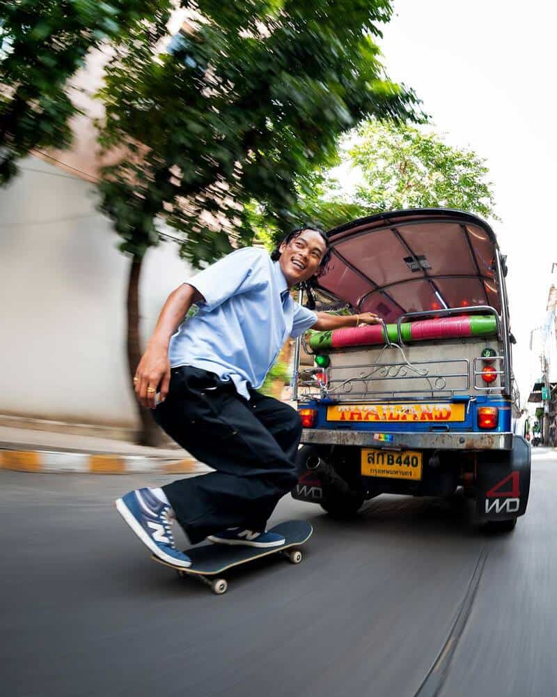 man on skateboard being pulled by a rickshaw